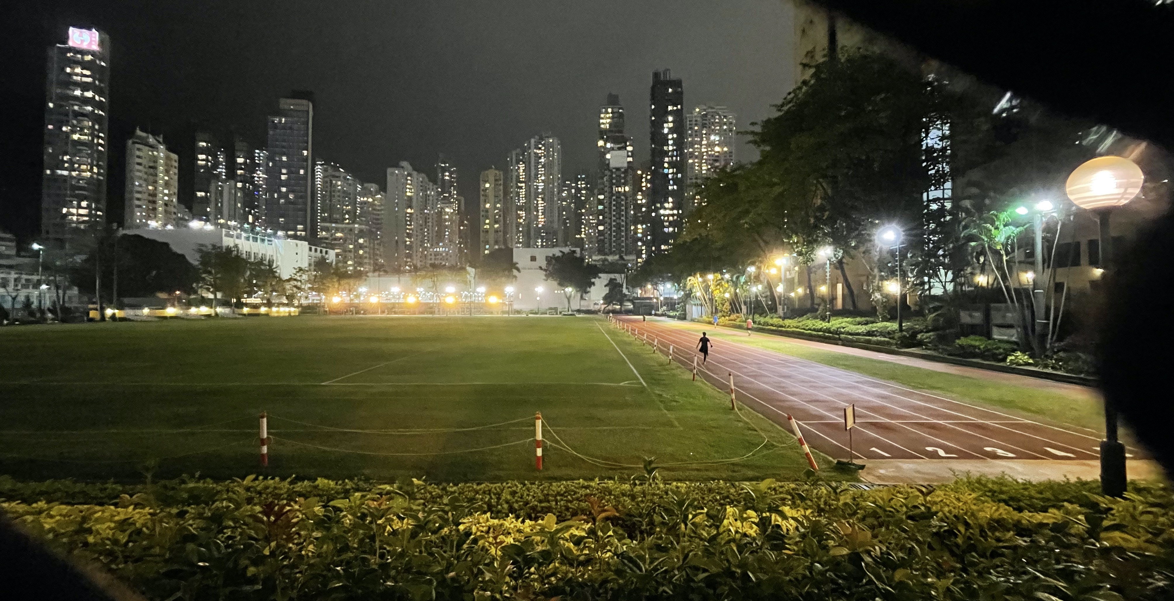 Runner at night on a Hong Kong track, with city behind