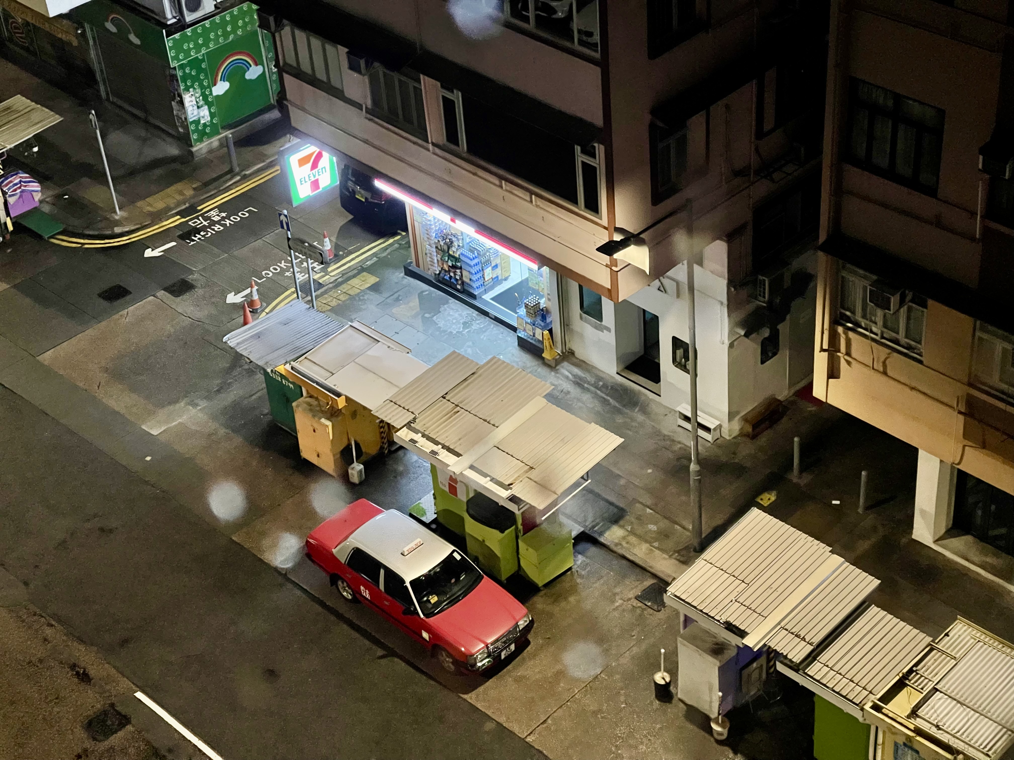 The 7-Eleven steps, benches, and a parked taxi in the rain